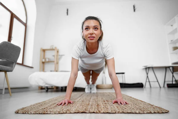 Sporty young woman doing plank exercise indoors at home — Stock Photo, Image