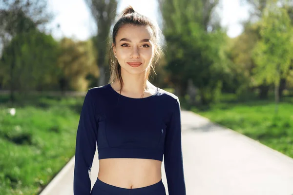 Portret van een jonge glimlachende vrouw die sportkleding draagt in het ochtendpark — Stockfoto