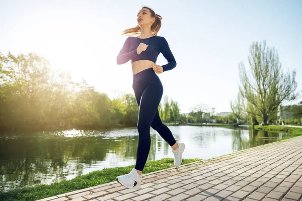 Atlético en forma joven mujer corriendo temprano en la mañana en el parque — Foto de Stock