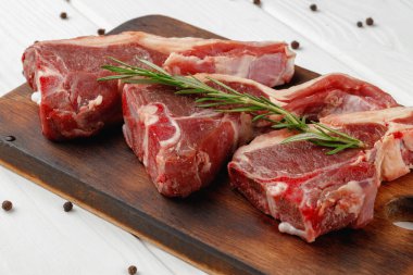 Beyaz arka planda tahta tahtada çiğ et kaburgaları.