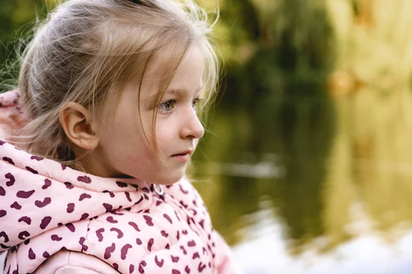 Petite fille assise dans le parc près du lac — Photo