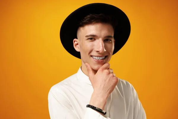 Portrait of a young stylish man wearing black hat against yellow background — Stock Photo, Image