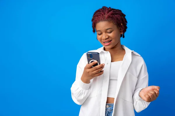 Mujer afroamericana usando smartphone contra fondo azul — Foto de Stock