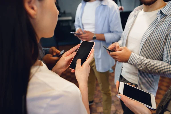 Olika ungdomar kollegor som arbetar med mobiltelefoner tillsammans på kontoret — Stockfoto