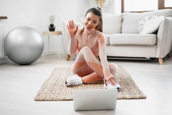 Jonge vrouw in sportkleding met behulp van laptop om training video tutorials kijken thuis — Stockfoto