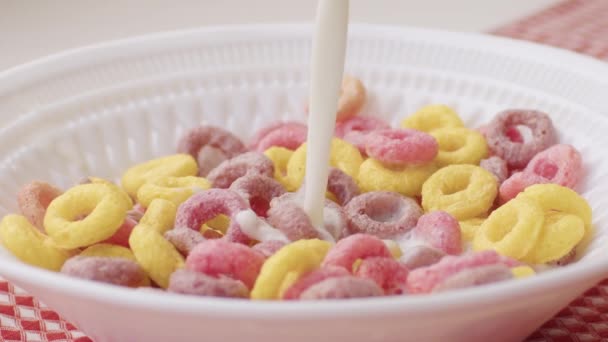 Разноцветные хлопья для завтрака в миске с брызгами молока — стоковое видео