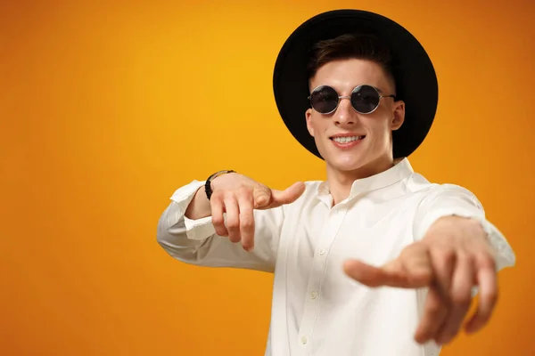 Retrato de un hombre joven y elegante con sombrero negro sobre fondo amarillo — Foto de Stock