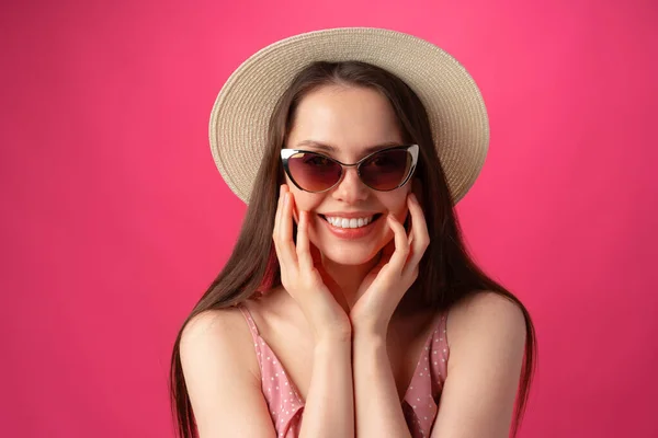 Modeporträt einer jungen attraktiven Frau mit Hut und Brille vor rosa Hintergrund — Stockfoto