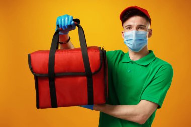 Termo çantalı yüz maskeli genç kurye.