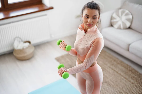 Sporty young woman exercising at home with dumbbells — Stock Photo, Image