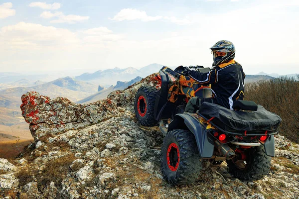 ヘルメットの男は山の中でATVクワッドバイクに座って — ストック写真