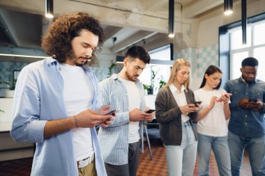 Ofiste cep telefonları üzerinde çalışan çeşitli genç insanlar