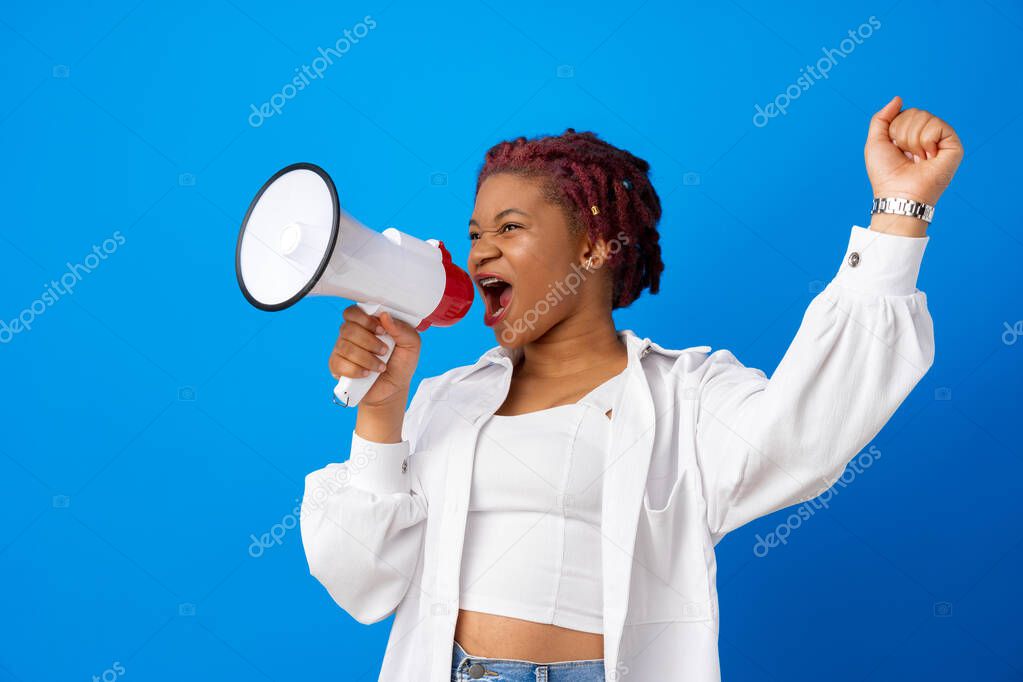 African american woman using megaphone against blue background