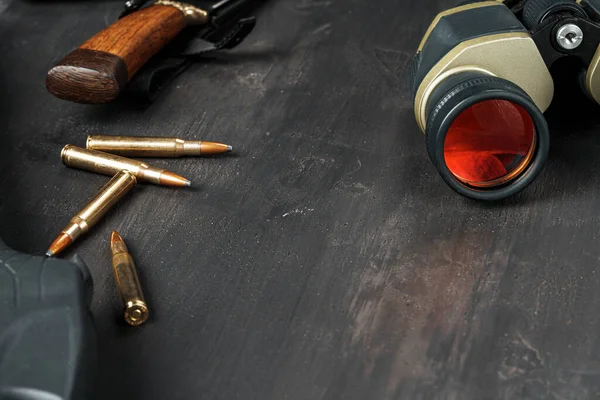 Hunting rifle and binoculars on dark wooden background — Stock Photo, Image