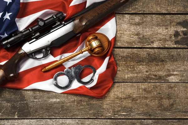 Wooden judge gavel and hunting rifle over USA flag on wooden background — Stock Photo, Image