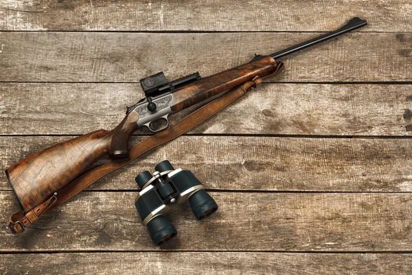 Κυνηγετικό όπλο και κιάλια σε σκούρο ξύλινο φόντο — Φωτογραφία Αρχείου