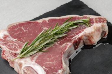 Gri masada yağda marine edilmiş çiğ biftek.