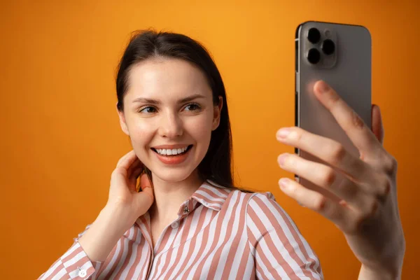Ritratto di giovane donna attraente che usa il suo smartphone su sfondo giallo — Foto Stock