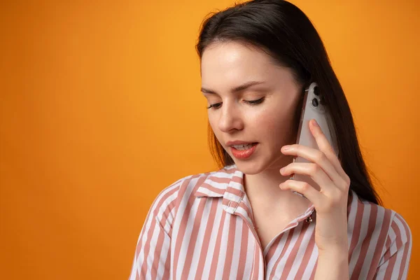Студійне фото молодої жінки, що розмовляє по телефону на жовтому тлі — стокове фото