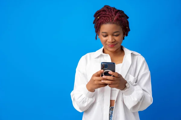 Mujer afroamericana usando smartphone contra fondo azul — Foto de Stock