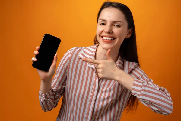 Feliz sorrindo jovem mulher mostrando-lhe tela de smartphone preto com espaço de cópia — Fotografia de Stock