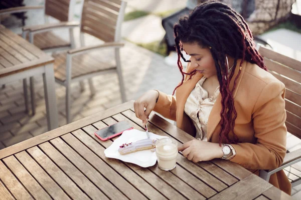 微笑着的非洲裔美国女人在户外咖啡馆喝咖啡和吃甜点 — 图库照片