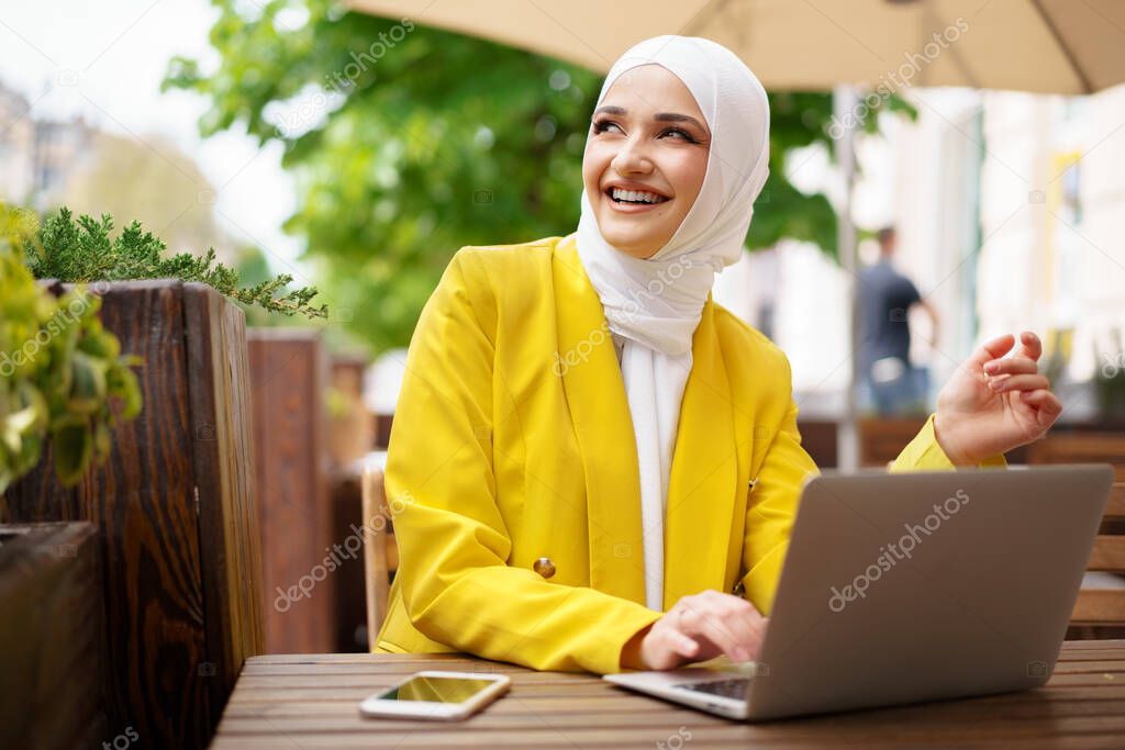 Beautiful smiling muslim woman with laptop at cafe