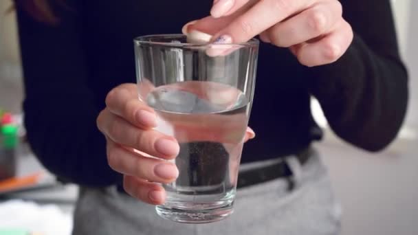 Close up of woman dropping effervescent tablet in glass with water — Stock Video