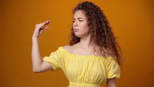 Jonge krullende vrouw toont bla-bla gebaar geïsoleerd op gele achtergrond — Stockvideo