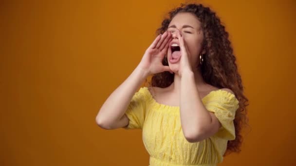 Ung lockigt hår kvinna skriker mot gul bakgrund — Stockvideo