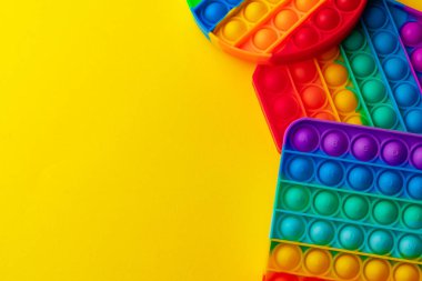 Renkli anti-stres oyuncağını sarı arka plana yerleştir