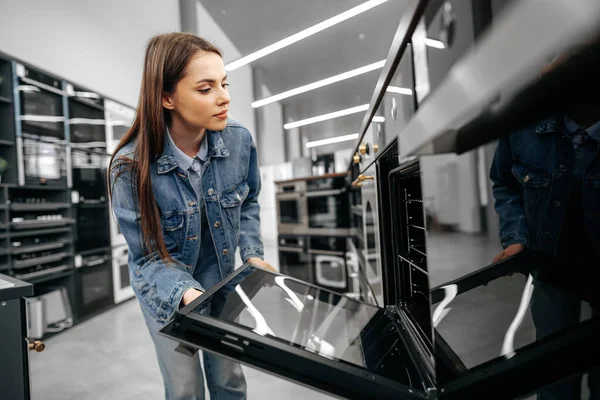 Ung kvinna letar efter ny elektrisk ugn i ett köpcentrum — Stockfoto