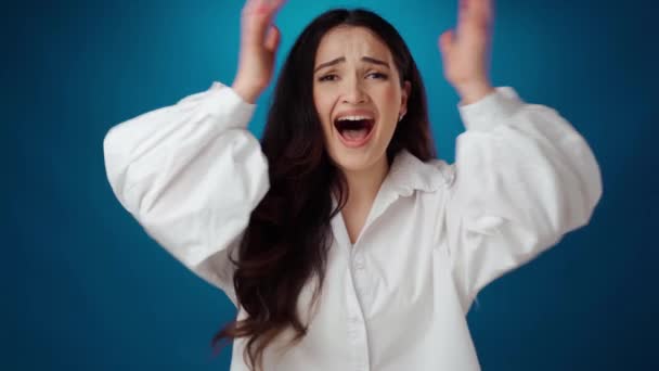 Frustrerad nervös kvinna skrikande nad röra huvudet mot blå bakgrund — Stockvideo