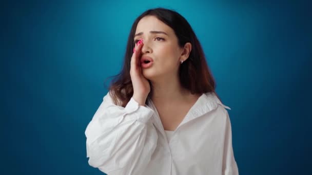 Молодая привлекательная женщина кричит на голубом фоне — стоковое видео