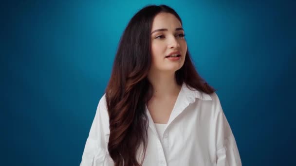 Stresset ung kvinde forsøger at falde til ro og trække vejret dybt mod blå baggrund – Stock-video