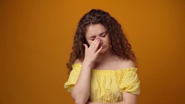 Trött sömnig ung lockig kvinna gäspar mot gul bakgrund — Stockvideo