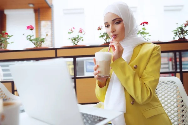 Mooie jonge moslim vrouw met behulp van laptop tijdens het zitten in cafe — Stockfoto