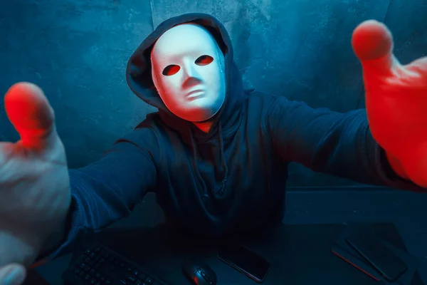 Hacker anónimo con máscara facial que trabaja en la computadora en la habitación oscura —  Fotos de Stock