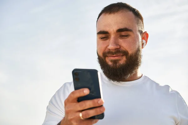 Fiatal férfi használja a mobiltelefon, miközben séta a vidéken — Stock Fotó