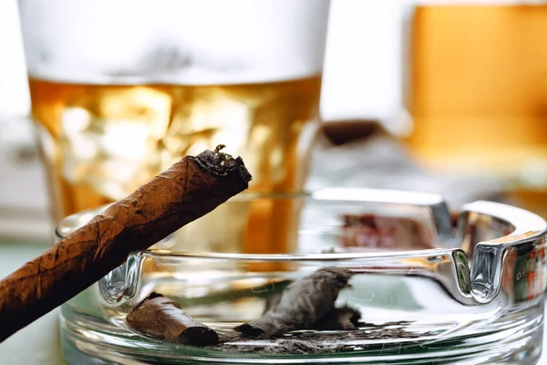 Close up de fumar charuto e copo de uísque na mesa — Fotografia de Stock