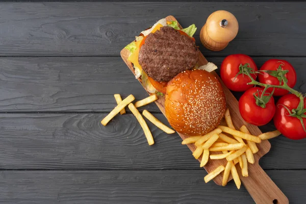 Свежий бургер и картошка фри на черном деревянном фоне — стоковое фото