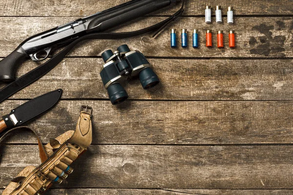 Equipo de caza sobre fondo de madera viejo incluyendo rifle, cuchillo, binoculares y cartuchos —  Fotos de Stock