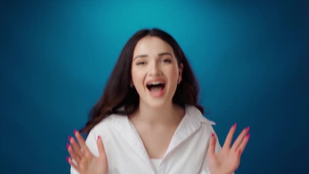 Surprised young woman celebrating success against blue background — Stock Video