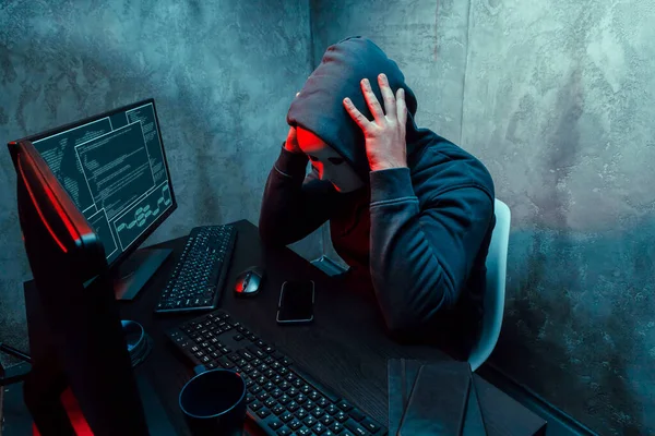 Anónimo hacker de Internet con máscara sentado en la mesa y utilizando el ordenador —  Fotos de Stock