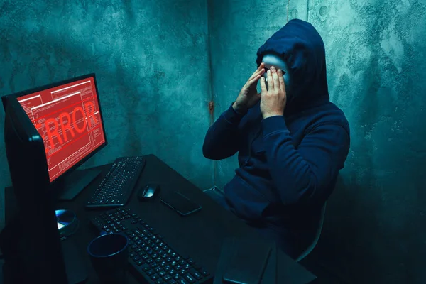 Hacker anónimo con máscara facial que trabaja en la computadora en la habitación oscura — Foto de Stock
