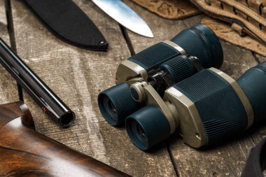 Tüfek, bıçak, dürbün ve fişekler de dahil olmak üzere eski ahşap arka planda avlanma ekipmanları.