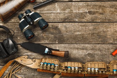 Tüfek, bıçak, dürbün ve fişekler de dahil olmak üzere eski ahşap arka planda avlanma ekipmanları.