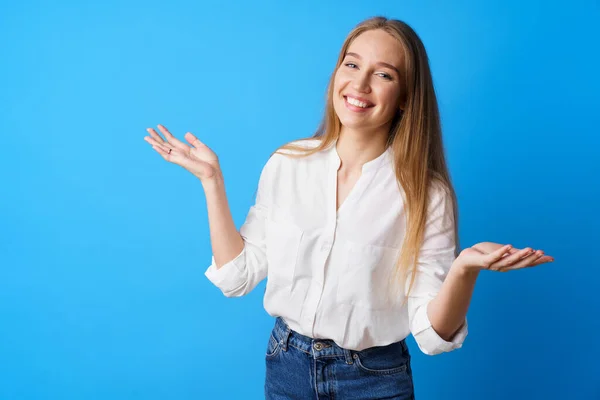 Förvånad ung blond kvinna kasta upp händerna mot beige bakgrund — Stockfoto