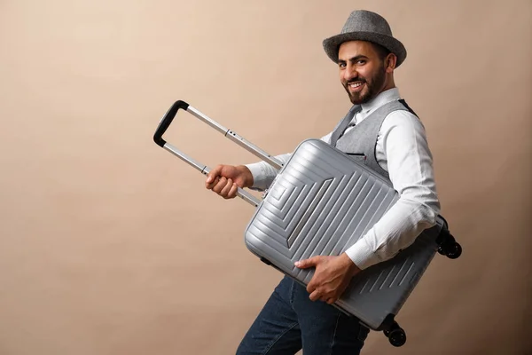 Happy arabski człowiek z walizką bagażu na beżowym tle — Zdjęcie stockowe