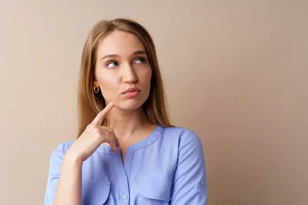 Joven empresaria pensativa pensando en alguna idea sobre fondo beige — Foto de Stock